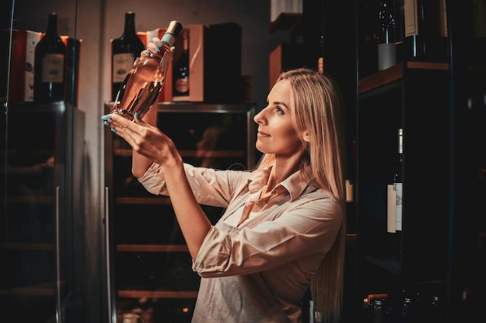 Une femme sort une bouteille de vin d'un frigo